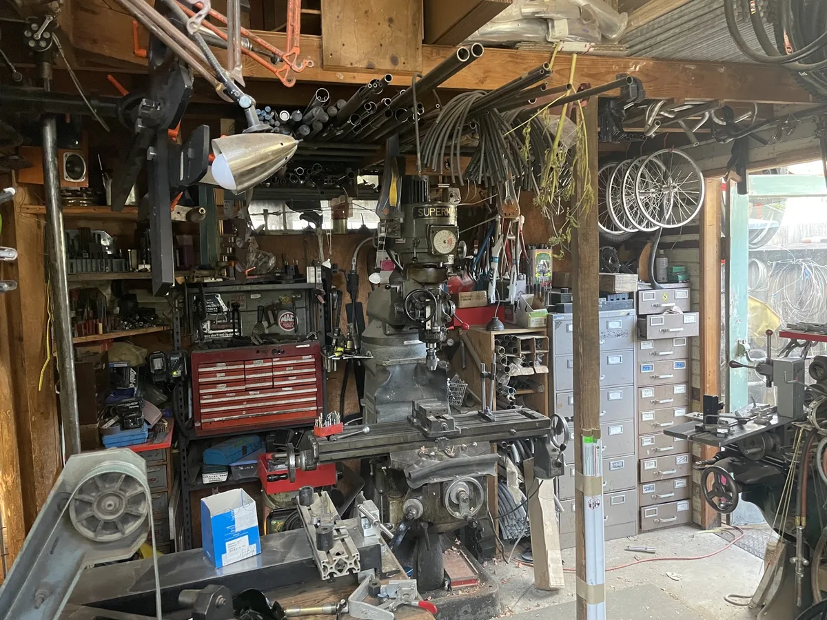 Atelier garage avec fraiseuse et tubes acier stockés au plafond à Santa Cruz